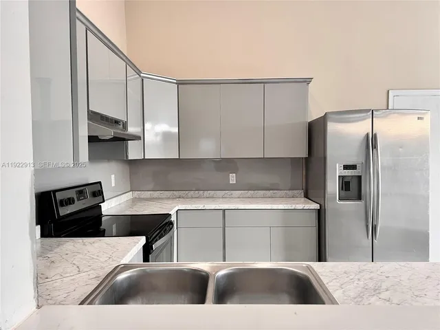 a kitchen with stainless steel appliances granite countertop a refrigerator a sink a stove and white cabinets