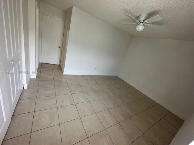 an empty room with a ceiling fan and glass door