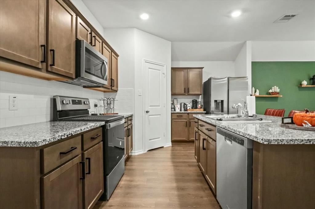 804 Roland Drive Fate, TX 75189 - Photo 16 of 27 a kitchen with stainless steel appliances granite countertop a sink stove and cabinets