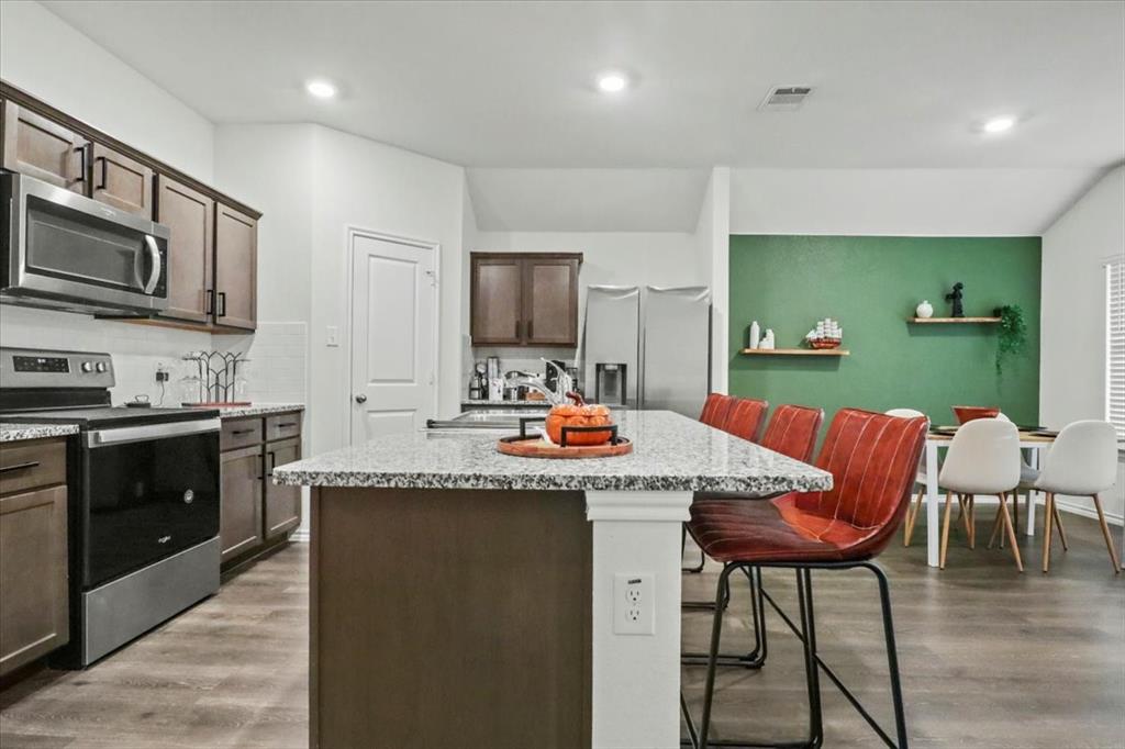 804 Roland Drive Fate, TX 75189 - Photo 17 of 27 a kitchen with stainless steel appliances kitchen island granite countertop a kitchen island and chairs in it