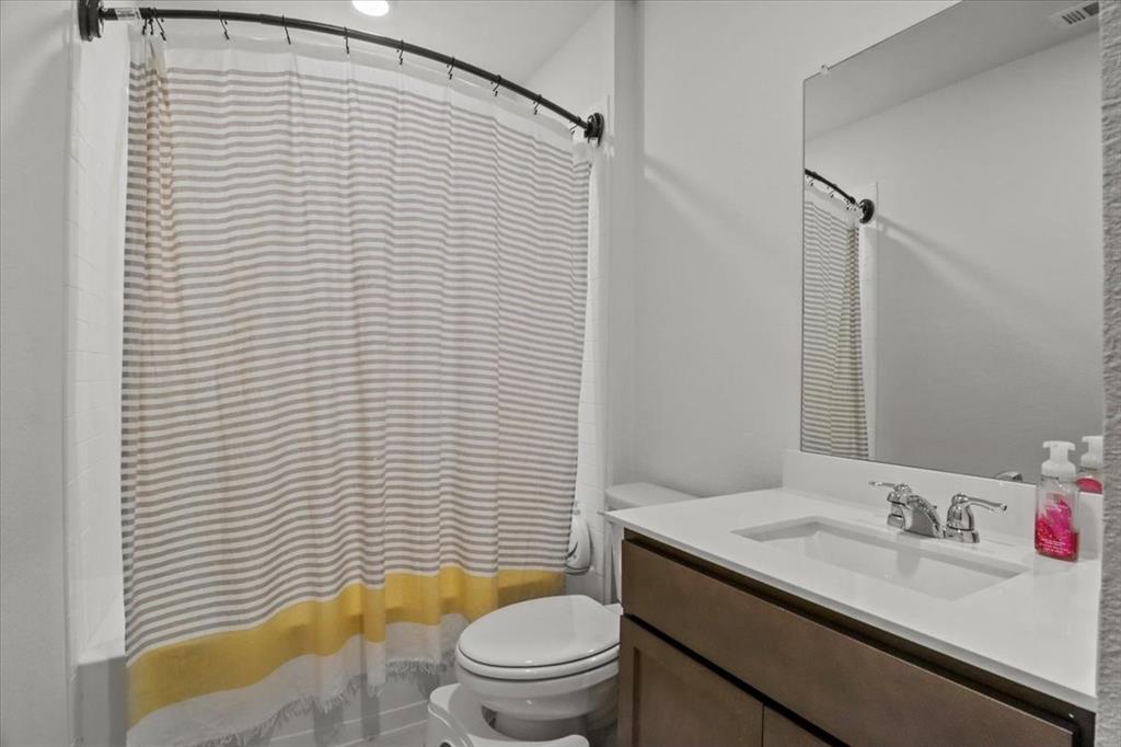 804 Roland Drive Fate, TX 75189 - Photo 21 of 27 a bathroom with a sink a toilet and shower curtain