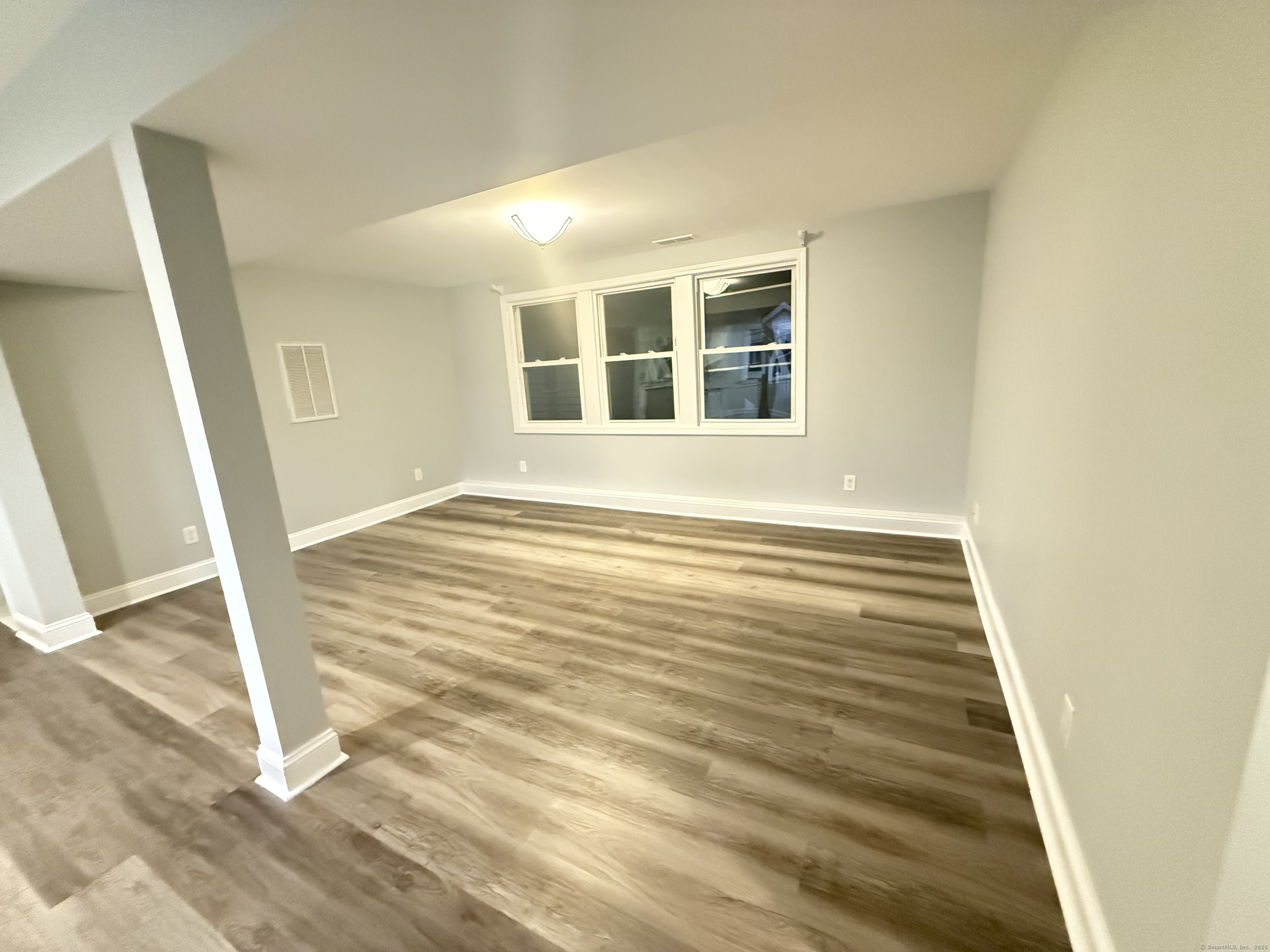 65 Muir Terrace, Unit 1 Southington, CT 06489 - Photo 3 of 24 a view of an empty room with wooden floor and a window