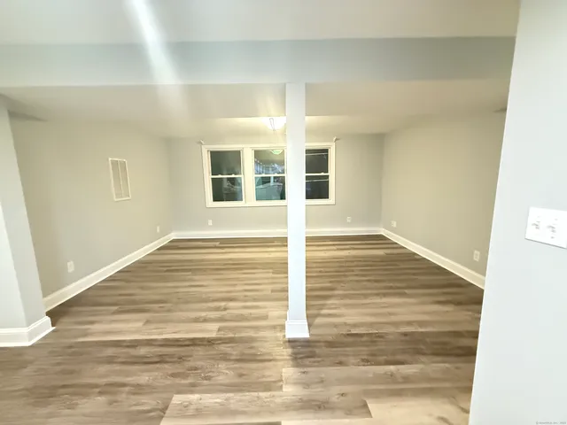a view of an empty room with wooden floor and windows