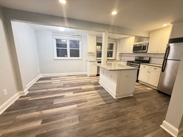 a living room with stainless steel appliances kitchen island granite countertop a stove and a sink