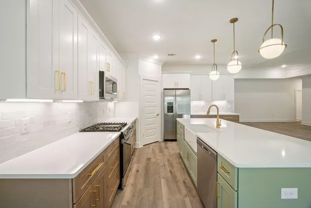 a large kitchen with kitchen island a stove a sink a chimney and a refrigerator