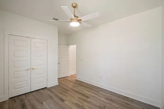 an empty room with wooden floor closet and entryway