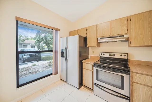 a kitchen with a stove a refrigerator and a view of living room