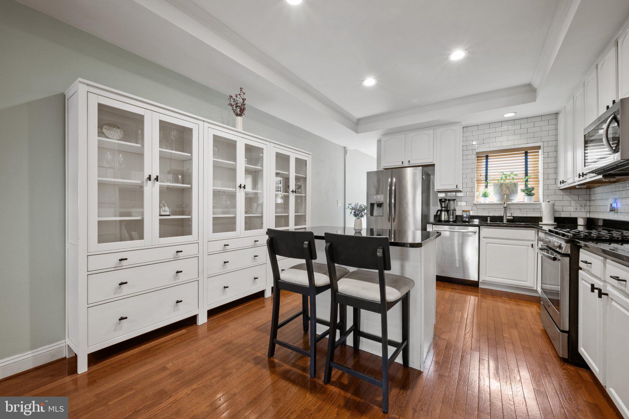 615 South Clinton Street Baltimore, MD 21224 - Photo 6 of 39 a kitchen with stainless steel appliances kitchen island granite countertop a stove a refrigerator a dining table and chairs with wooden floor