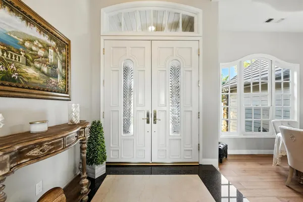 a large white kitchen with a large island oven a stove a dining table and chairs with wooden floor