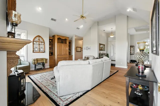 a large white kitchen with a large island oven a stove a dining table and chairs with wooden floor