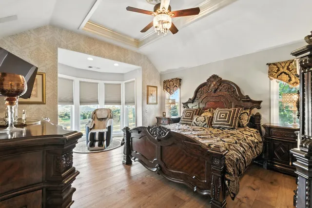 a bedroom with a bed a couch and a flat tv screen on dresser