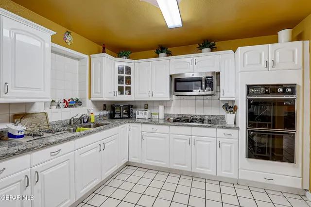 a kitchen with stainless steel appliances granite countertop a stove a sink and a microwave