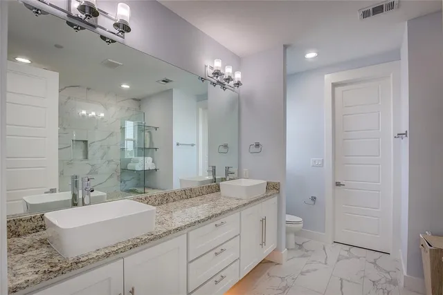 a bathroom with a granite countertop sink a mirror and a shower