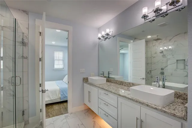a spacious bathroom with a granite countertop sink a mirror and a shower