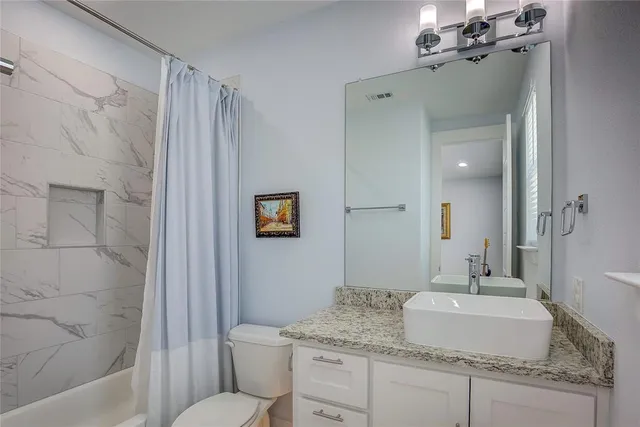 a bathroom with a granite countertop sink toilet and shower