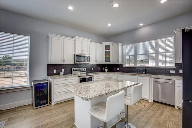 a kitchen with stainless steel appliances granite countertop a sink a stove a refrigerator a center island and cabinets