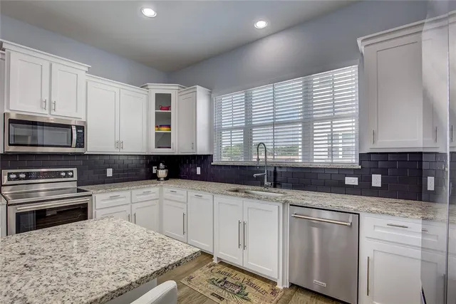 a kitchen with stainless steel appliances granite countertop a sink stove and cabinets