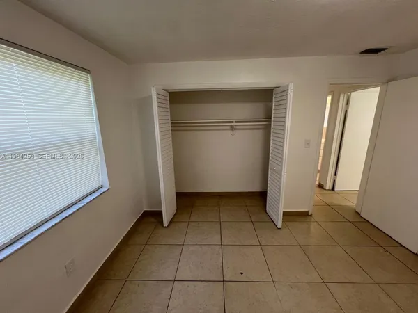 a view of a refrigerator in kitchen and an empty room in wooden floor
