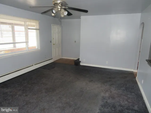 en empty room with windows and chandelier fan