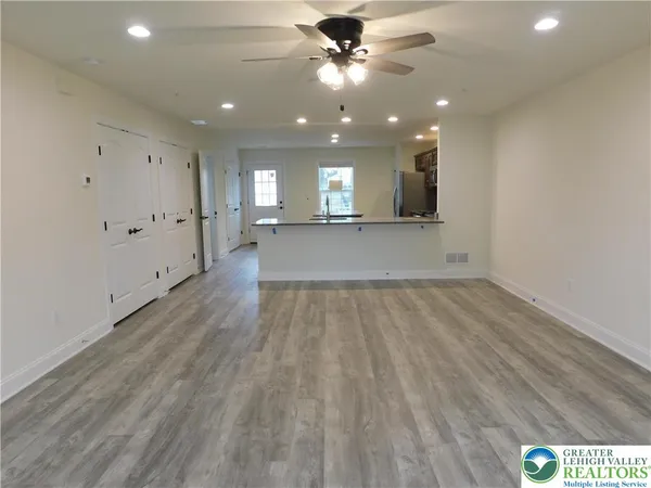 an empty room with wooden floor and a ceiling fan
