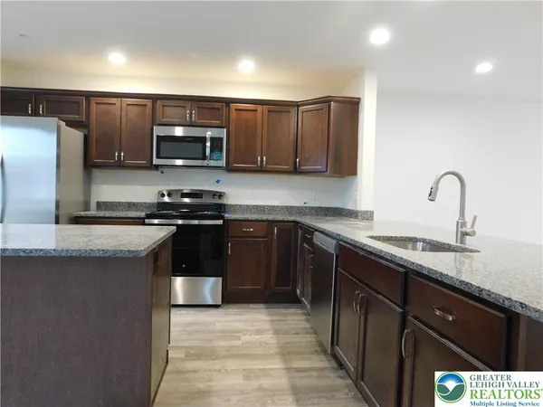 a kitchen with stainless steel appliances granite countertop a stove a sink and a refrigerator
