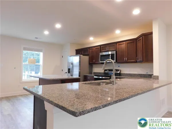 a kitchen with stainless steel appliances granite countertop a sink a stove and a microwave