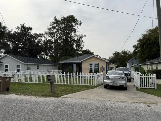 a view of a house with a small yard and large trees