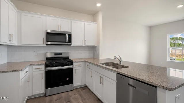 a kitchen with granite countertop white cabinets sink and stainless steel appliances