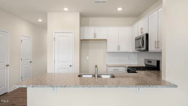 a kitchen with stainless steel appliances granite countertop a sink a stove and a refrigerator