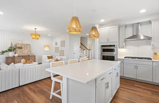 a large kitchen with kitchen island a stove a sink a refrigerator and white cabinets with wooden floor