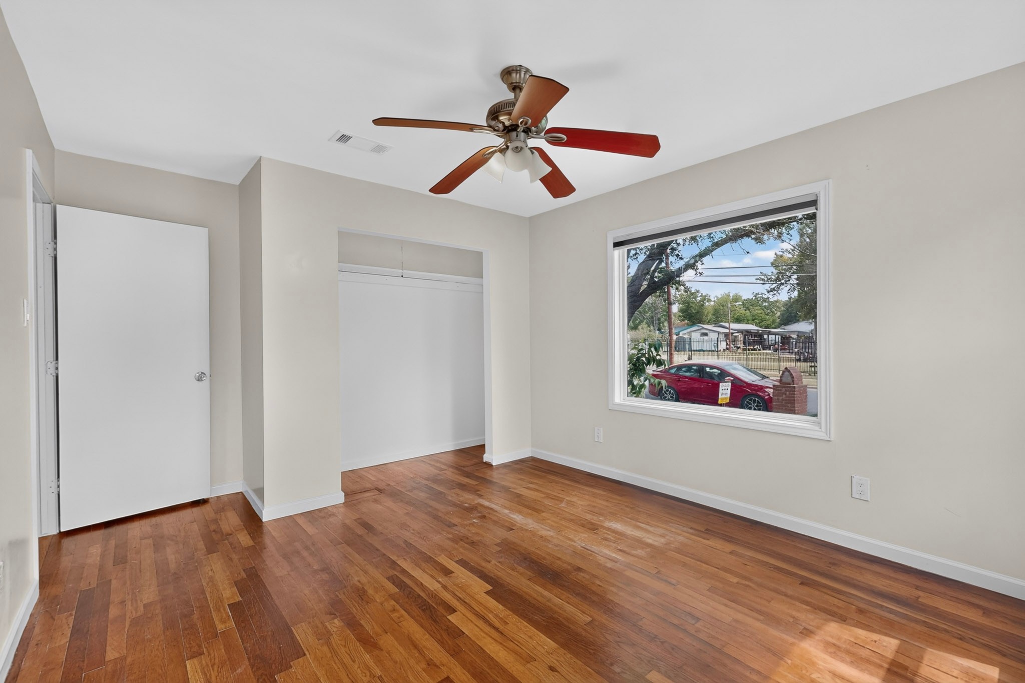4711 Alf Avenue Austin, TX 78721 - Photo 19 of 34 BR1 - A well-lit bedroom with hardwood floors, an open closet, and a street-facing window.