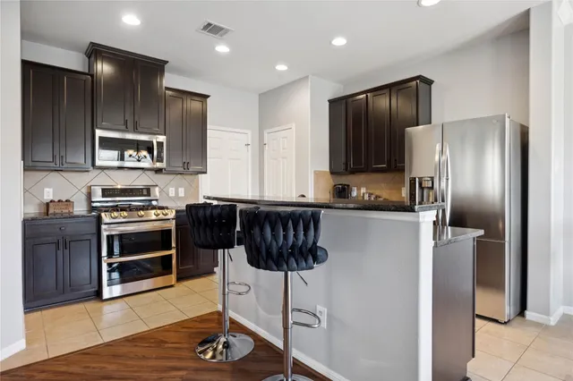 a kitchen with stainless steel appliances granite countertop a sink a stove and a refrigerator