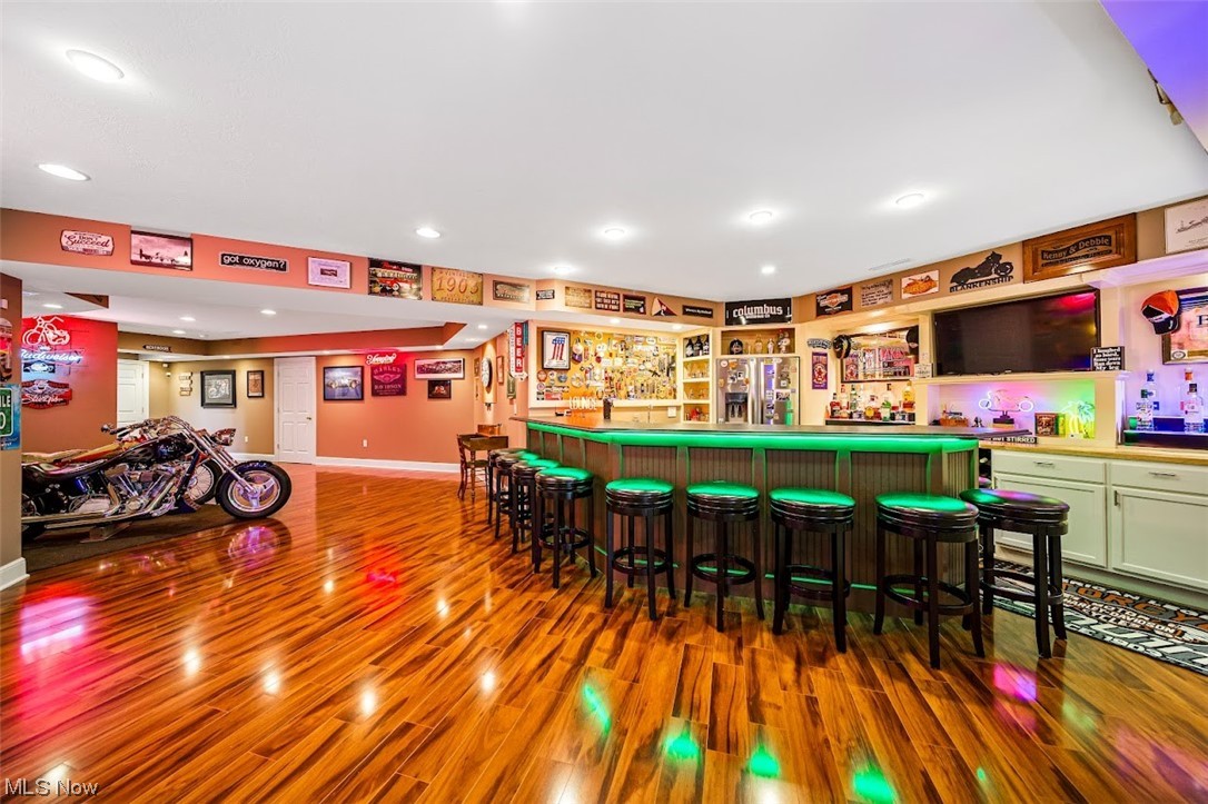 12151 Girdled Road Painesville, OH 44077 - Photo 28 of 35 Bar with hardwood / wood-style floors, green cabinets, and stainless steel refrigerator with ice dispenser