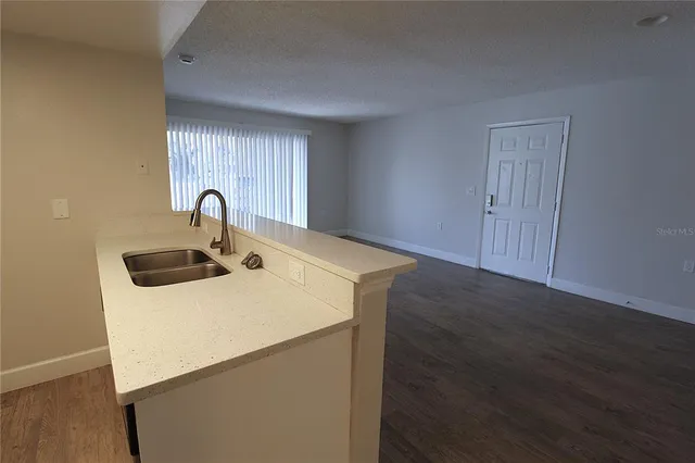 a kitchen with a sink a refrigerator and wooden floor