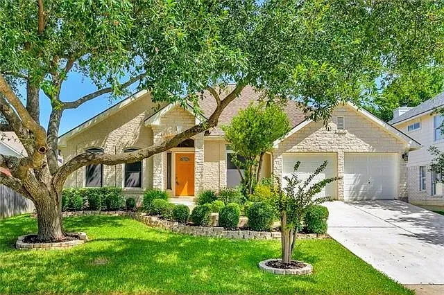 a front view of a house with a yard and large tree