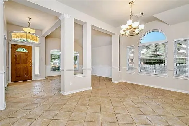 an empty room with chandelier and glass door