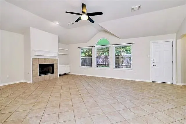 a view of an empty room with a window and kitchen view