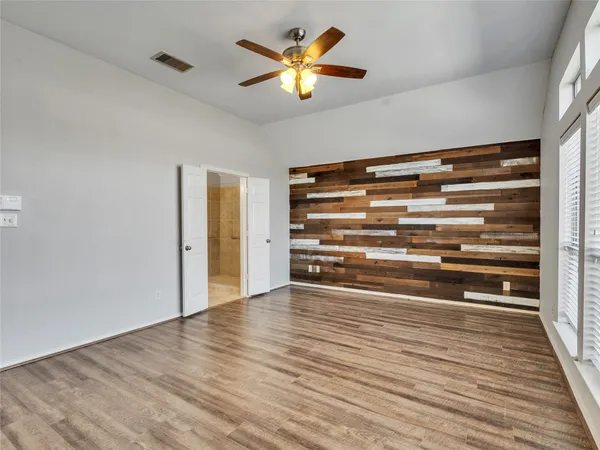 a view of an empty room with window and chandelier fan