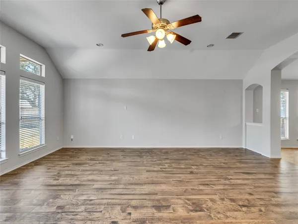 a view of empty room with wooden floor and fan