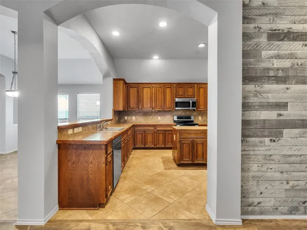 an empty room with wooden floor chandelier fan and windows