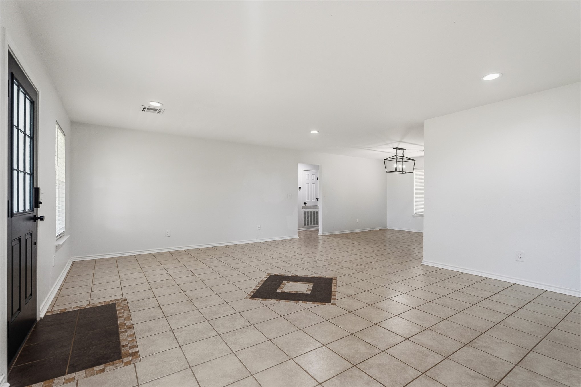 831 Barrons Ridge Wilson, OK 73463 - Photo 13 of 47 Spacious open-concept room featuring light-toned tile flooring with a central accent, recessed lighting, and a modern geometric chandelier
