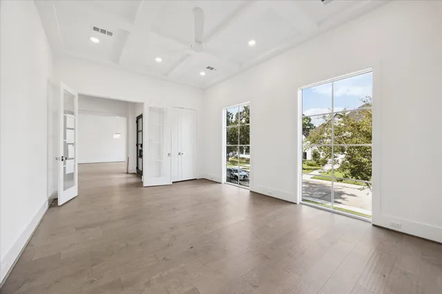 an empty room with wooden floor and windows