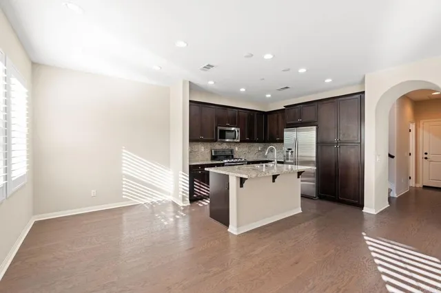 a kitchen with stainless steel appliances kitchen island granite countertop a refrigerator and a sink