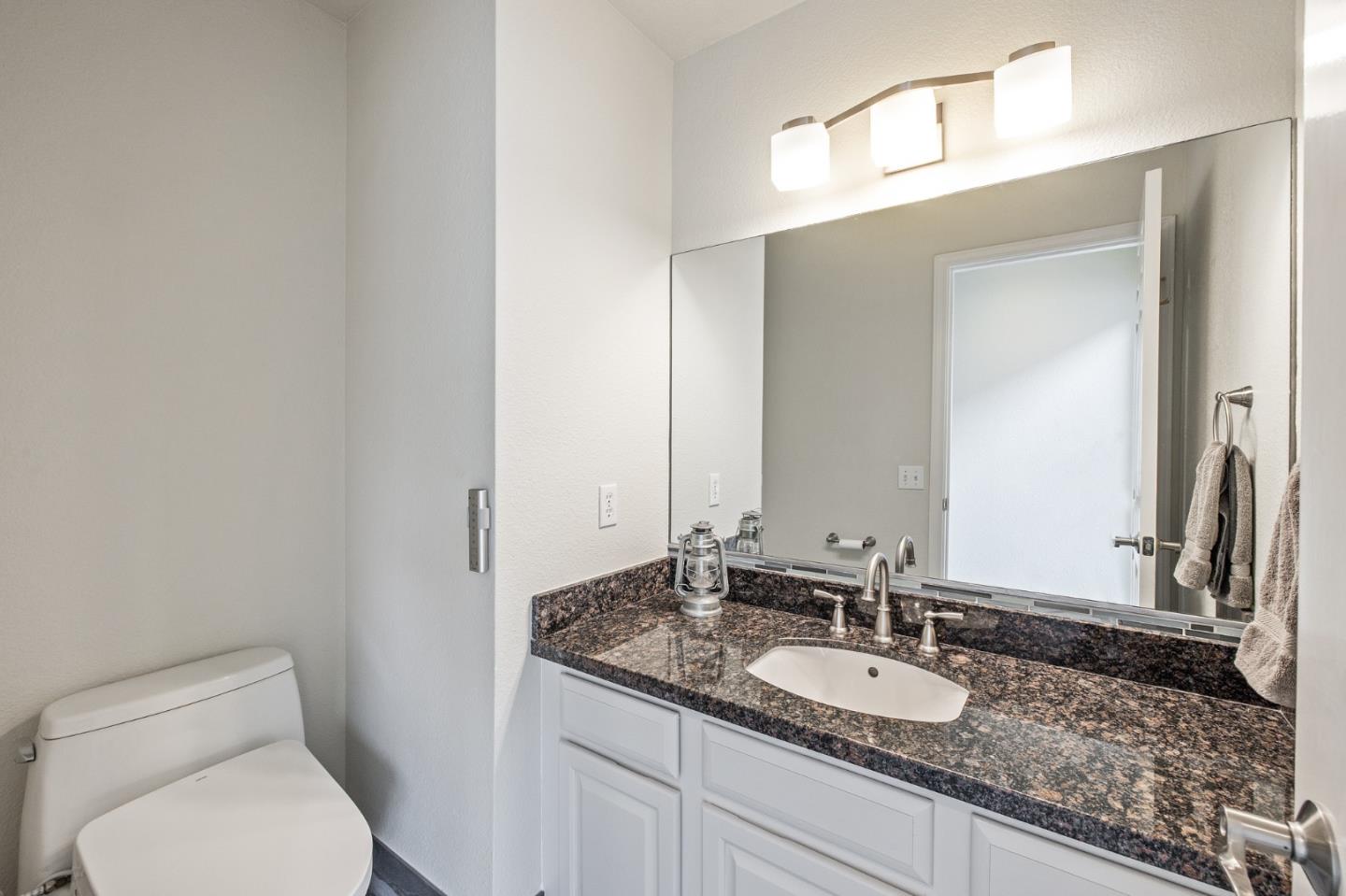 226 Palma Street El Granada, CA 94018 - Photo 16 of 41 a bathroom with a granite countertop toilet sink and mirror