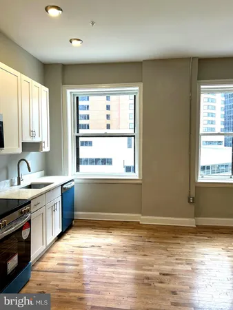 a view of a kitchen with kitchen island a sink wooden floor and a large window