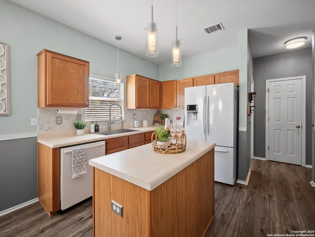 a kitchen with stainless steel appliances a sink a stove a refrigerator cabinets and wooden floor