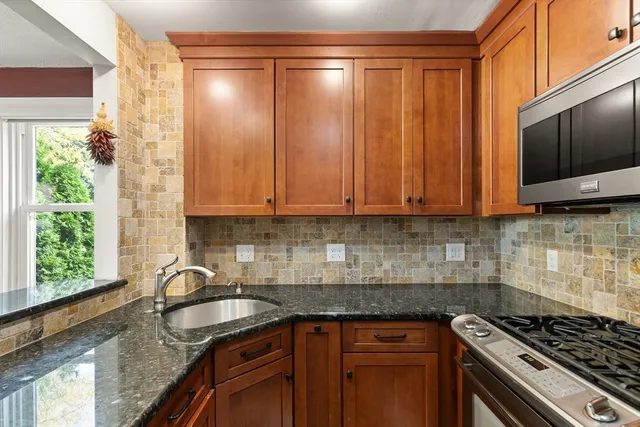 a kitchen with stainless steel appliances granite countertop a stove a sink and a microwave