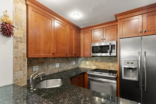 a kitchen with granite countertop a sink stainless steel appliances and cabinets
