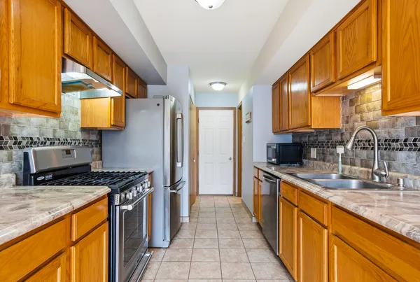 a kitchen with stainless steel appliances granite countertop a sink a stove and a refrigerator