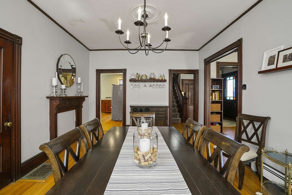 a dining room with wooden floor a chandelier a wooden table and chairs